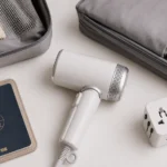 Folded travel hair dryer packed with passport and plug adapter for international travel