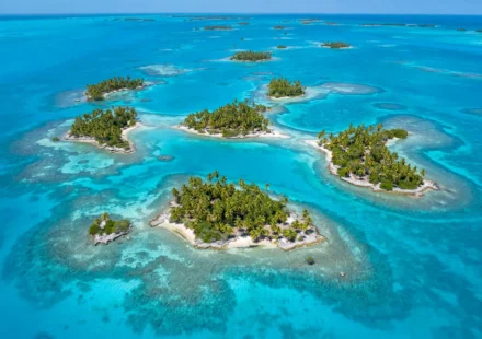 Aerial view of the San Blas Islands in Panama with turquoise water and palm trees under clear dry-season skies.