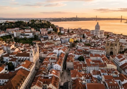 Terracotta rooftops of Lisbon at sunset with the Tagus River in the distance