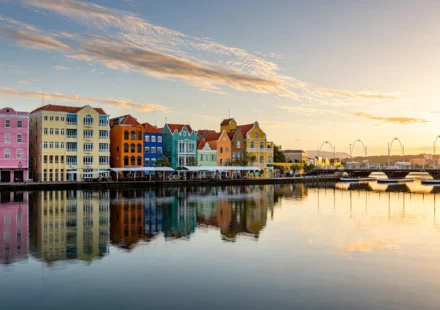 Colorful Dutch colonial buildings along the Willemstad waterfront in Curacao at golden hour.